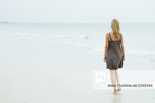 Frau im Sonnenkleid am Strand  Rückansicht