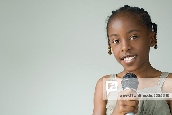 Little girl holding microphone  smiling at camera  portrait