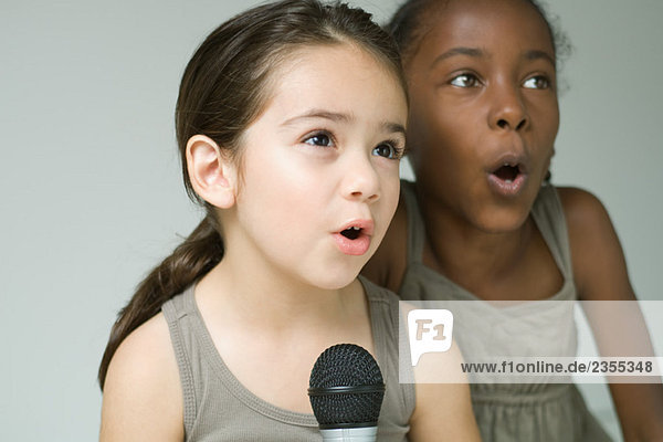 Zwei kleine Mädchen singen zusammen ins Mikrofon  Nahaufnahme