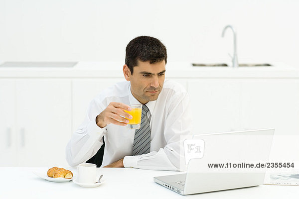 Mann beim Frühstück und mit Laptop