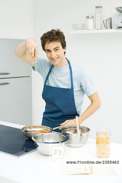 Junger Mann beim Kochen  lächelnd vor der Kamera