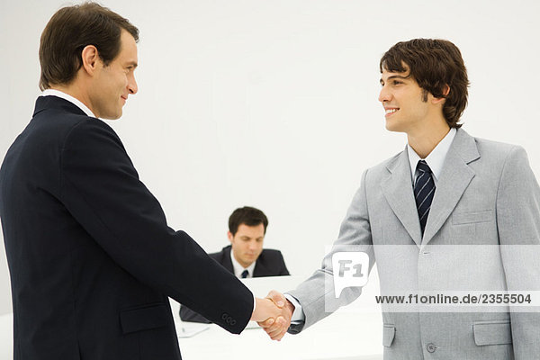 Two businessmen shaking hands  smiling at each other