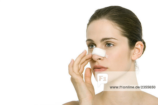 Junge Frau mit Bandage auf der Nase  wegblickend