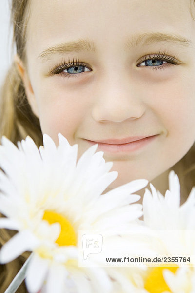 Kleines Mädchen mit Gerbera-Gänseblümchen  lächelnd vor der Kamera  Portrait