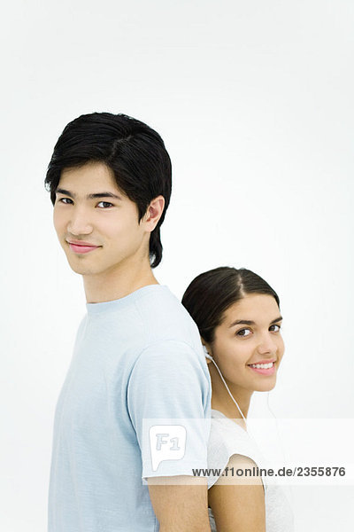 Junger Mann und Frau stehen Rücken an Rücken  lächelnd vor der Kamera  Porträt