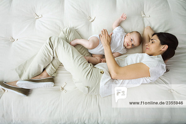 Mother and infant lying together on bed  high angle view