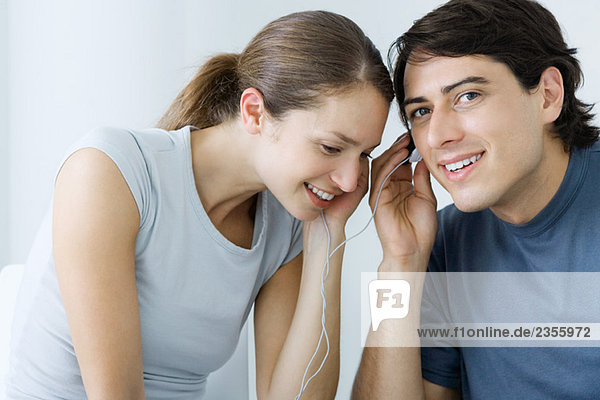 Couple listening to earphones together  smiling