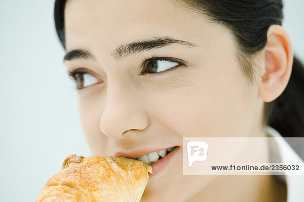 Junge Frau beim Croissantessen  Nahaufnahme