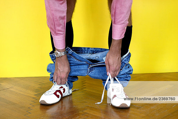 Mann mit Hosen unten Bindungsaufhebung in seiner shoes'laces