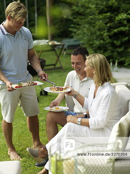 Mann mit Essen an seine Freunde auf einer Gartenparty