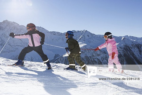 Children walking up slope with skis on
