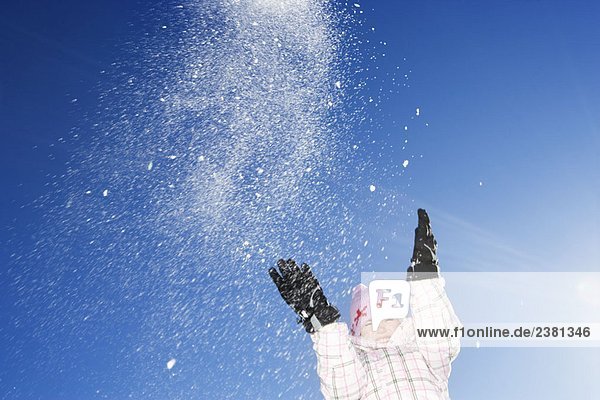 Junges Mädchen wirft Schnee in die Luft