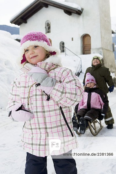 Kinder spielen mit Schlitten im Schnee