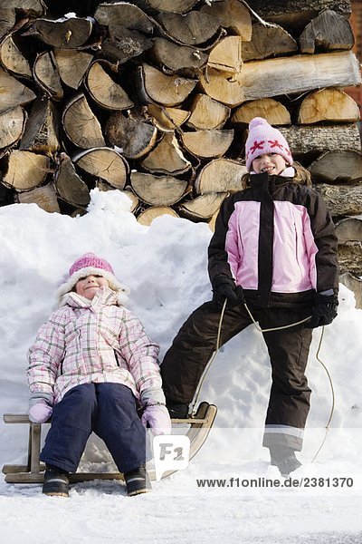 Junge Mädchen posieren mit Schlitten auf Schnee