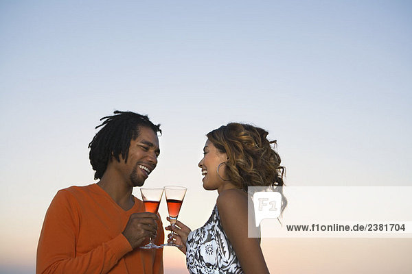 Junges Paar trinkt Wein bei Sonnenuntergang