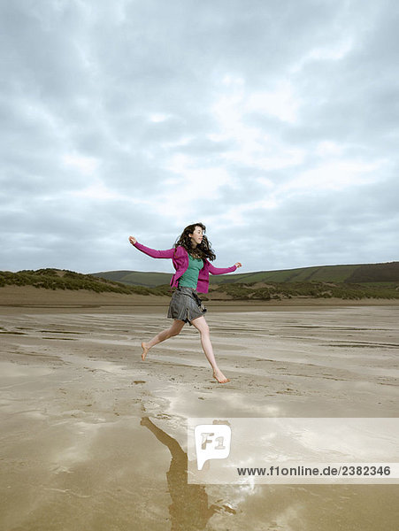 Junge Frau beim Springen am Strand