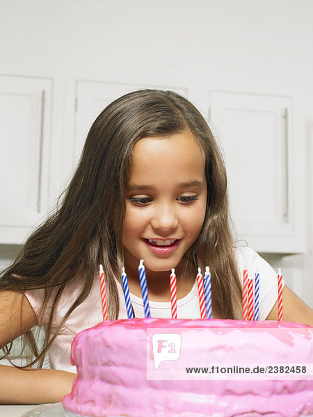Mädchen (8-10) schaut auf Kuchen mit Kerzen