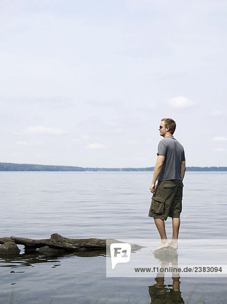 Mann steht auf einem Felsen im flachen Wasser