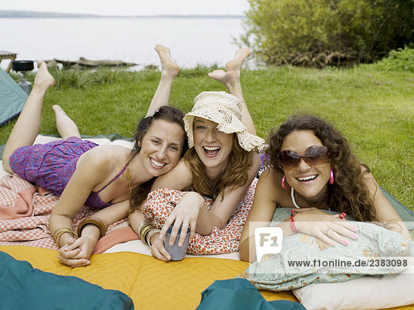 Drei Frauen lächelnd auf Decken liegend