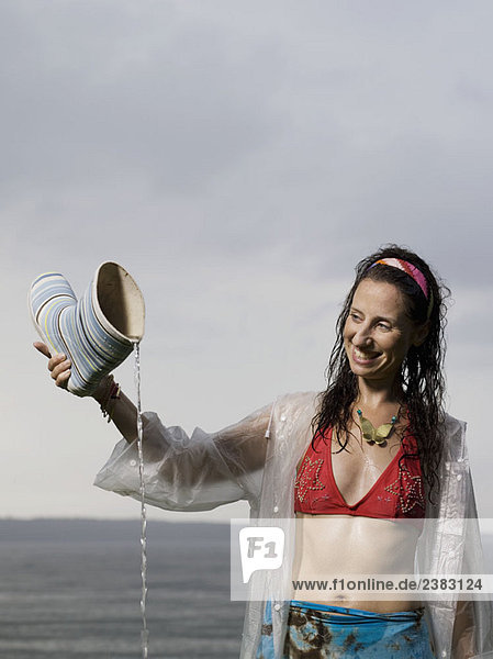 Frau schüttet Wasser aus Gummistiefel aus