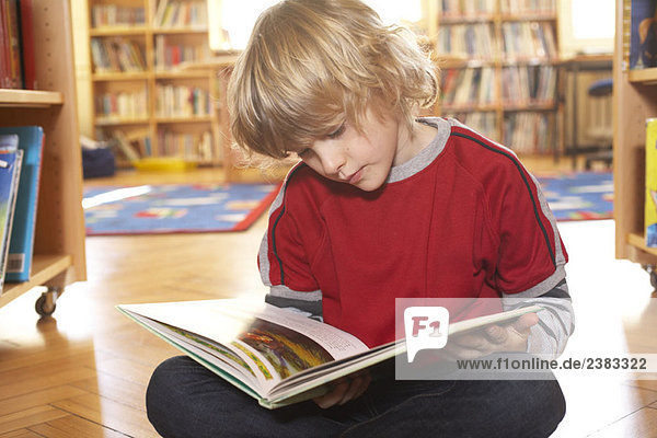 Boy reading a book on the floor