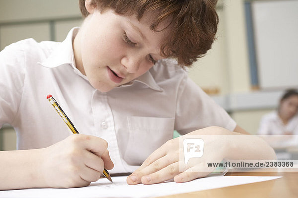 Junge schreibt im Klassenzimmer