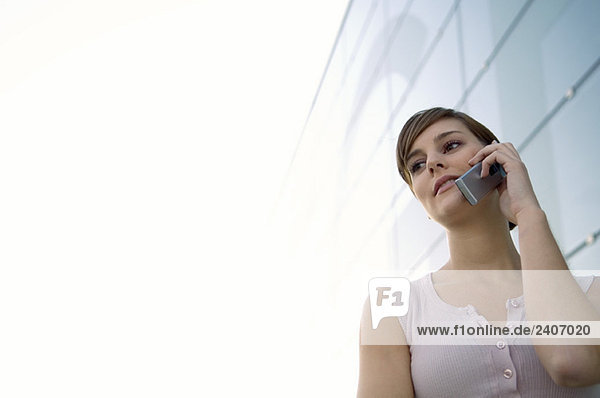 Niederwinkelansicht einer jungen Frau  die auf einem Handy spricht
