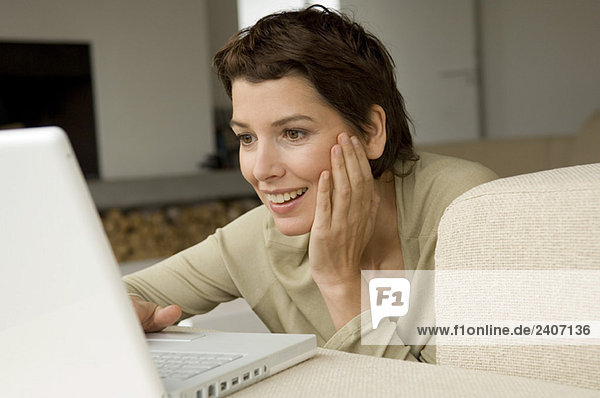 Mittlere erwachsene Frau bei der Arbeit am Laptop im Wohnzimmer