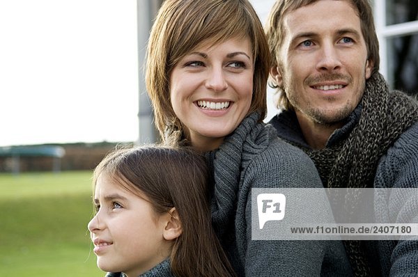 Close-up of a girl looking away with her parents smiling