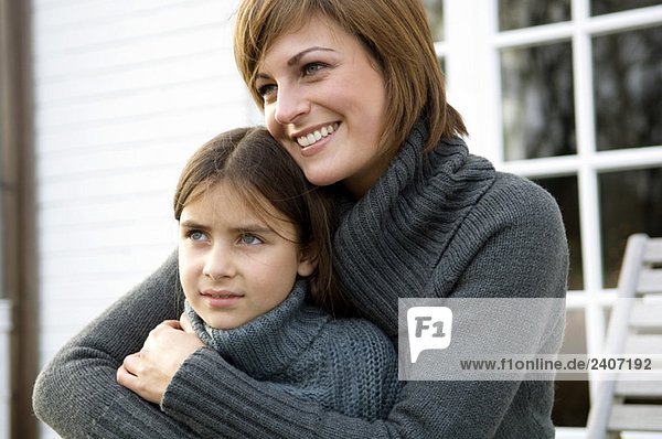 Close-up of a young woman hugging her daughter and smiling