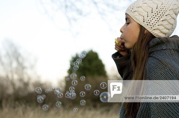 Seitenprofil eines Mädchens  das Blasen mit einem Blasenstab bläst.