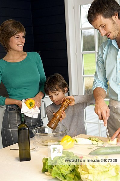 Ein erwachsener Mann und eine junge Frau  die mit ihrem Sohn Essen zubereiten.