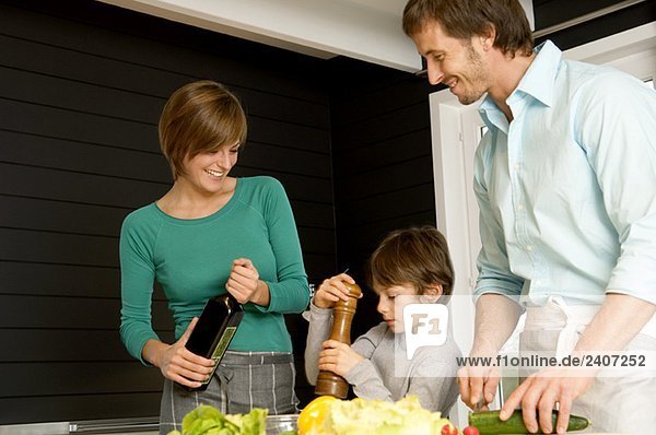 Ein erwachsener Mann und eine junge Frau  die mit ihrem Sohn in der Küche Essen zubereiten.