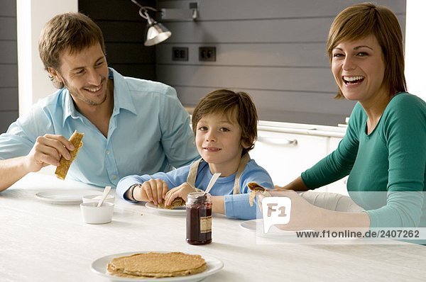 Ein erwachsener Mann und eine junge Frau beim Frühstück mit ihrem Sohn.