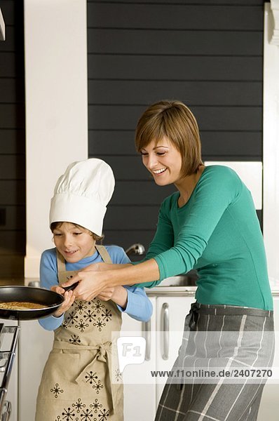 Junge Frau bei der Zubereitung eines Pfannkuchens mit ihrem Sohn