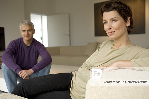 Mid adult woman and a mature man sitting in a living room