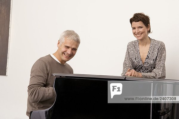 Porträt eines reifen Mannes am Klavier und einer erwachsenen Frau in seiner Nähe