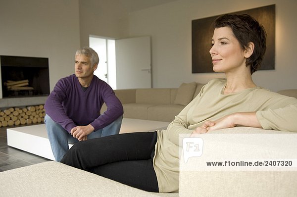 Mature man and a mid adult woman sitting in a living room