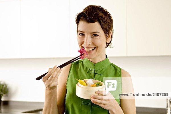 Porträt einer erwachsenen Frau beim Essen mit Essstäbchen