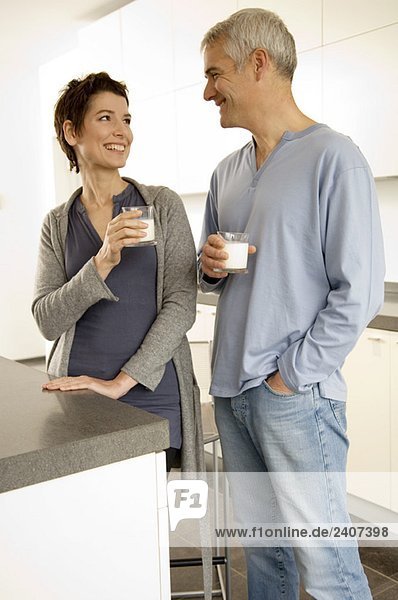Mature man and a mid adult woman holding glasses of milk