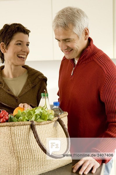 Ein reifer Mann und eine erwachsene Frau  die in der Küche stehen.