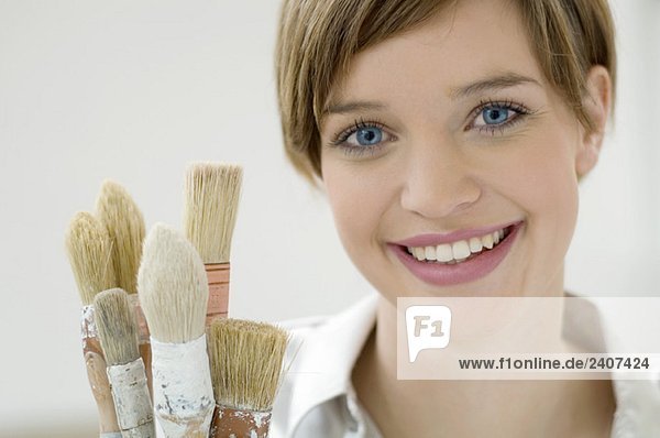 Portrait of a young woman holding paintbrushes
