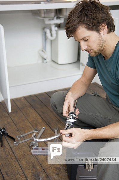 Mid adult man repairing a faucet in the kitchen