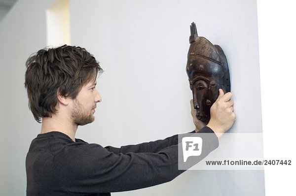 Mid adult man adjusting a mask on a wall