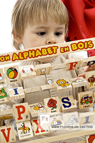 Nahaufnahme eines kleinen Jungen beim Spielen mit Alphabetblöcken