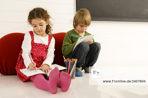 Junge und Mädchen zeichnen auf Notizblöcken