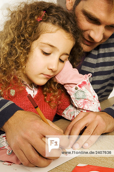 Mittlerer Erwachsener Mann hilft seiner Tochter beim Zeichnen