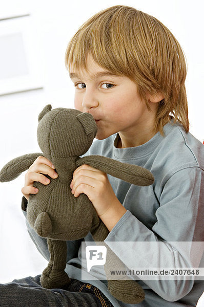 Porträt eines Jungen  der einen Teddybären küsst
