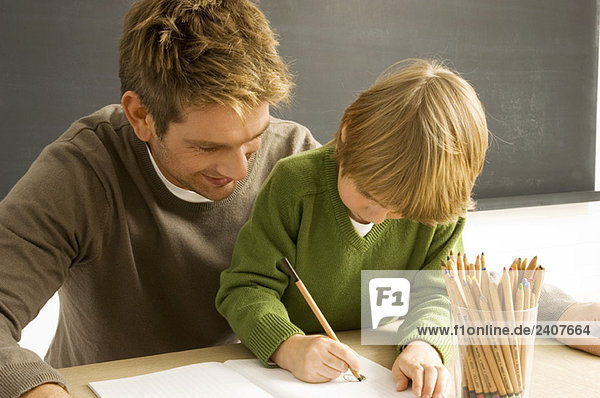 Mittlerer Erwachsener Mann hilft seinem Sohn beim Zeichnen