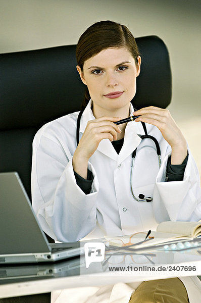 Porträt einer Ärztin  die an einem Schreibtisch in ihrem Büro sitzt.